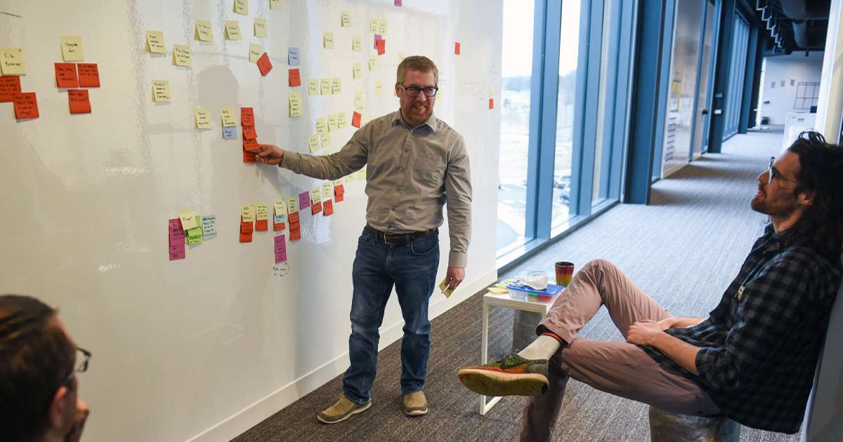 software developers collaborating at whiteboard with sticky notes